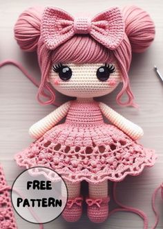 a crocheted doll with pink hair and dress sitting next to knitting needles on a white surface