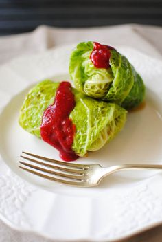 two pieces of lettuce with ketchup on a plate next to a fork