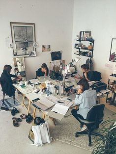 a group of people sitting around a table working on papers and laptops in an office