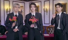 three young men in suits and ties standing next to each other with flowers on their lapels