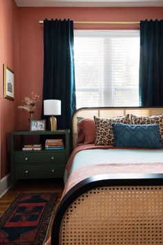 a bedroom with pink walls and black curtains, leopard print bedding, an animal print throw pillow, and green nightstands