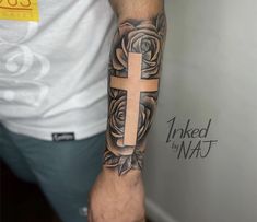 a man's arm with a cross and roses tattoo on the left side of his arm