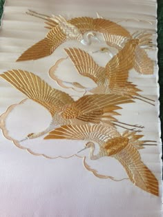 two golden birds on white fabric with green grass