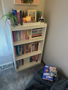 a bookshelf filled with lots of books next to a window and a plant