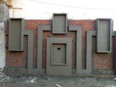 a brick wall with four cement niches on it