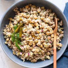 a bowl filled with food next to a wooden spoon on top of a white table