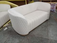 a white couch sitting on top of a floor next to a wooden table and chair