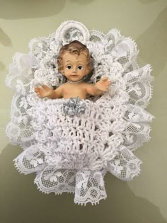 a small doll is laying in a crochet doily