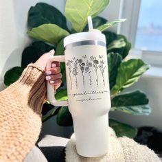 a person holding a coffee mug with flowers on it