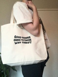 a woman holding a white tote bag that says, good things come to those who thirst