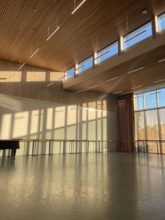 an empty room with large windows and a piano