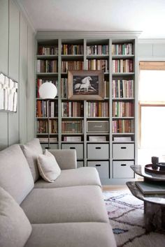 a living room filled with lots of furniture and bookshelves full of books on top of them