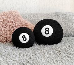 two black and white balls with numbers on them sitting on a gray blanket next to a pink teddy bear