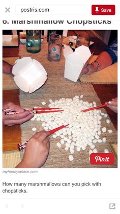 two people are making marshmallows with chopsticks on a wooden table