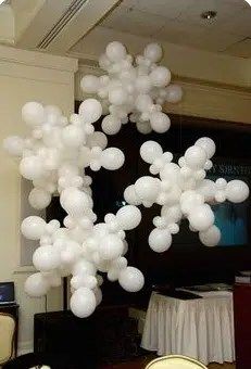 a bunch of white balloons are floating in the air over chairs and table cloths