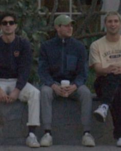 four young men sitting on top of cement blocks