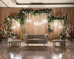 a couch sitting in front of a wall with flowers and chandeliers on it