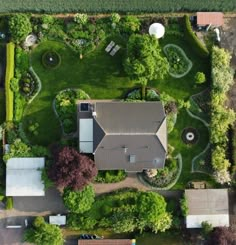 an aerial view of a house in the middle of a green yard with lots of trees