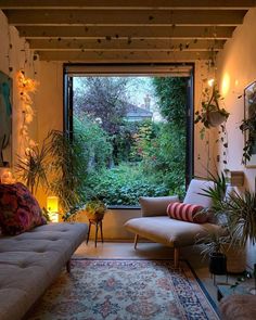 a living room filled with lots of plants next to a large window covered in greenery