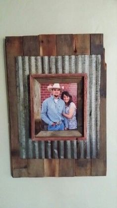 a wooden frame with a couple in it hanging on the wall next to a brick wall