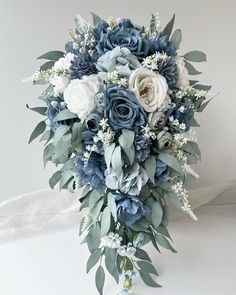 a bridal bouquet with blue flowers and greenery on the bottom, in front of a white background