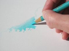 a person is holding a pencil and drawing with blue crayons on white paper