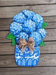 a blue and white vase filled with flowers on top of a wooden table next to a wall