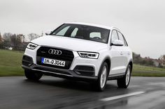 a white audi suv driving down the road