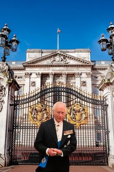 an old man standing in front of a building with a gate and flags on it