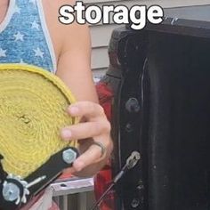 a woman holding a yellow piece of cloth next to a black suitcase with the words storage on it