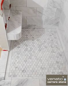 a bathroom with white marble tile and hexagonal pattern on the floor, along with red accents