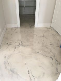 an empty room with white walls and marble flooring on the ground, in front of two doors