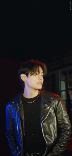 a young man wearing a black shirt and leather jacket