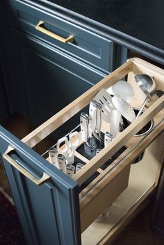 an open drawer in a kitchen with silverware and utensils on the drawers