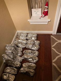 the elf is sitting on the floor next to some tin foil wrapped cookies in front of him