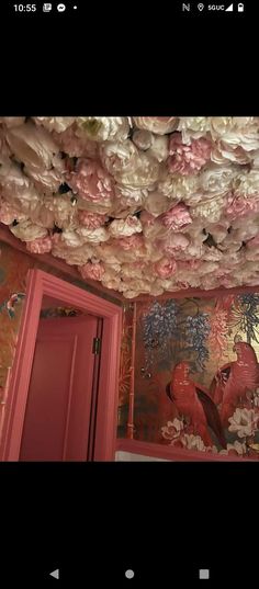 pink flowers are hanging from the ceiling in a room with red doors and wallpaper