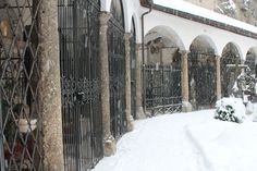 a snow covered courtyard with wrought iron gates and potted plants in the foreground