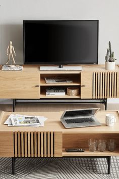 a living room with a television, coffee table and vases on the sidelines