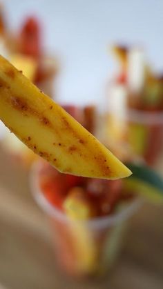 a banana sticking out of a small cup filled with fruit