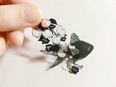 a hand is holding an origami fish with flowers on it's tail