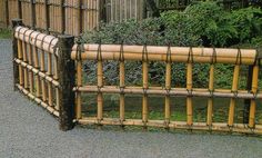 a close up of a bamboo fence with trees in the background