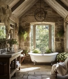 an old fashioned bathroom with stone walls and exposed ceiling, white bathtub surrounded by greenery