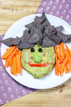 a plate with chips, carrots and guacamole in the shape of a face