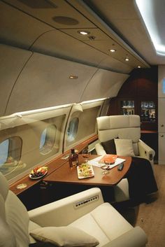 the inside of an airplane with leather seats and tables on each side of the plane