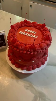 a red birthday cake sitting on top of a white plate next to a small card