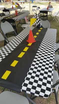 a long table covered in black and white checkered cloth with an orange cone on top