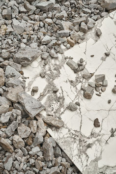 a broken umbrella laying on top of rocks and gravel with it's reflection in the mirror