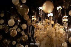 a chandelier hanging from the ceiling filled with white and silver balloons, streamers and lights