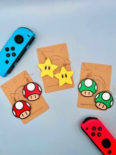 three nintendo themed earrings are on top of brown paper with yellow stars and two red dices