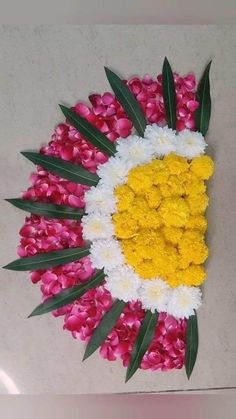 flowers and leaves arranged in the shape of a sunflower on a white surface with pink and yellow petals